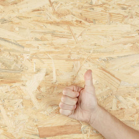 thumbs up on the background of a wooden board from osb sheet. like on a building sheet