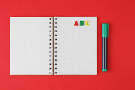 Notebook with ABC letters and colored markers on a red background, flat lay, English dayの写真素材