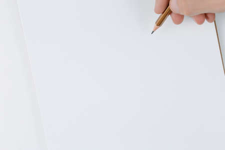 notepad in his hands on white background top view, boy writes into the notebook the to-do list for the new year, flat layの写真素材