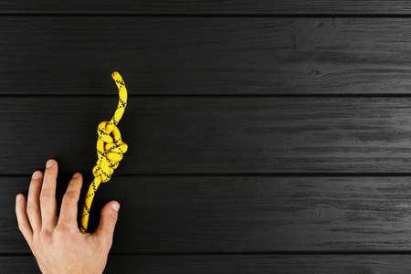 yellow rope in hands on a black wooden background, rope on the floor top viewの写真素材