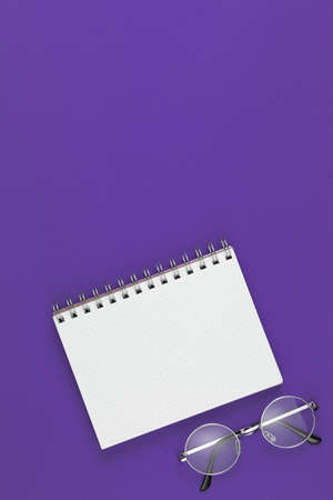 notebook with glasses on the violet background, school notebook on the purple desk, office desk with notebookの写真素材