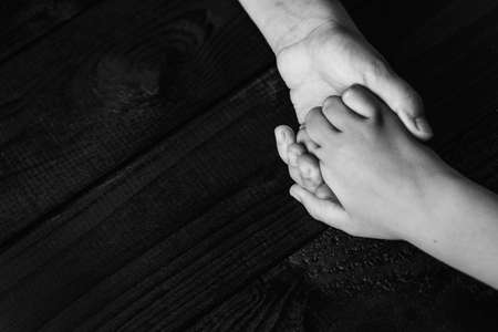 top view arms stretches out and holds one another on black wooden background. joint support and...