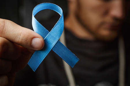 top view on hands holding prostate cancer ribbon, colon cancer concept, blue ribbon symbolの写真素材