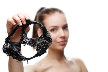girl takes off a black cosmetic mask from her face, Skin care face, isolated on a white backgroundの写真素材