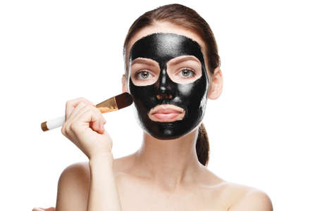 girl with black cosmetic mask on face, face cleaning at home isolated on white backgroundの写真素材