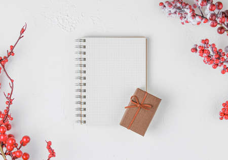 schoole notepad on white background with red berries and gifts, holiday concept flat lay. new goals, plans and to do list top view.の写真素材