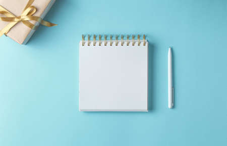 white notebook on a blue background with gifts, holiday concept flat lay. new goals, plans and to do list top view.の写真素材