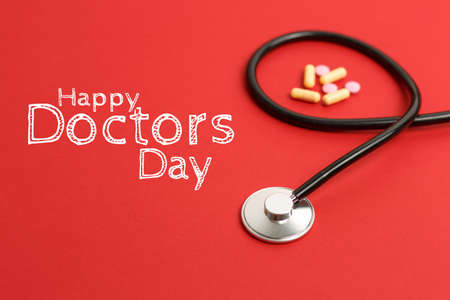 doctors day stethoscope on a red background with pills, free space, concept medicine and doctors office, dentists table with medicinesの写真素材