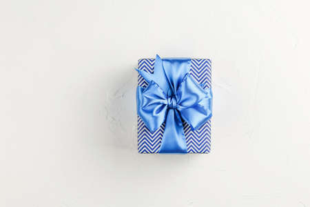 Gift box with blue ribbon on white background top view. Discount gift for sale day. Flat lay with copy space. Holiday concept.の写真素材