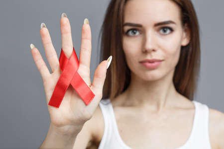 female hands holding red AIDS awareness ribbon, healthcare and medicine conceptの写真素材
