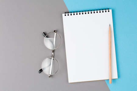 open notebook with white pencil on blue and gray table top view, notepad with blank page. flat lay of office conceptの写真素材