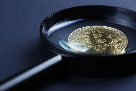 coin bitcoin under a magnifying glass on a dark background, extraction of crypto currencyの写真素材