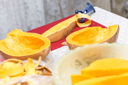 hands peel the vegetables from the skin, cutting off a thin layer on the kitchen. cooking orange pumpkin for brew and boiling healthy porridgeの写真素材