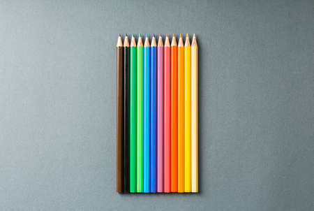 colored pencils in row on a gray background top view. Art set of pencils for schoolboy with free...