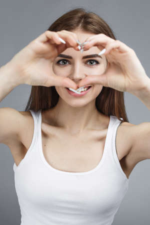 Close-up portrait of nicelooking cute cheerful cheery girl showing heart gesture isolated over gray  backgroundの写真素材