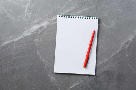 open notebook with red pen on marble  top view, school notepad on a dark table, office desk flat lay