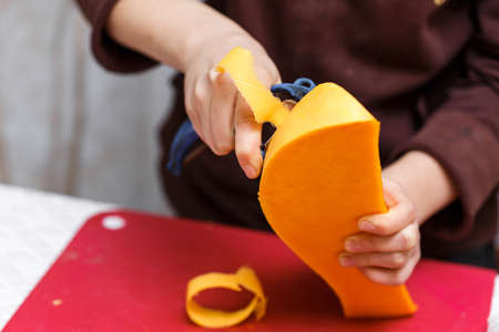hands peel the vegetables from the skin, cutting off a thin layer on the kitchen. cooking orange pumpkin for brew and boiling healthy porridgeの写真素材