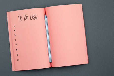 to do list Living Coral Notebook with pencil on gray background top view. blank notepad lies in the center of table, office concept flat lay.の写真素材