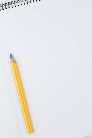 open notebook with yellow pencil on white table top view, spiral notepad with blank page. flat lay...