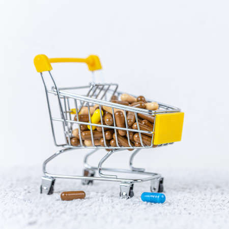 Pills in a shopping trolley on white background. Medical preparations on table. Insurance medicine concept.の写真素材