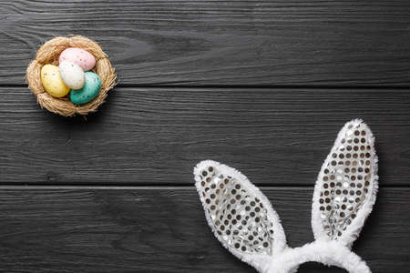 Easter minimal concept top view. Bunny rabbit ears on black wooden background flat lay with space...