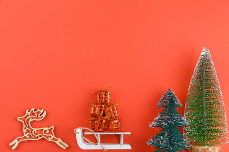Toy deer with a sleigh carries gifts on red background. christmas concept. new year compositionの写真素材