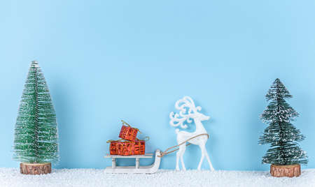 Toy deer with a sleigh carries gifts on blue background. christmas concept. new year composition