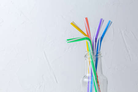 Multicolored tubules for drinks in transparent glass bottle on white background. cocktail day conceptの写真素材