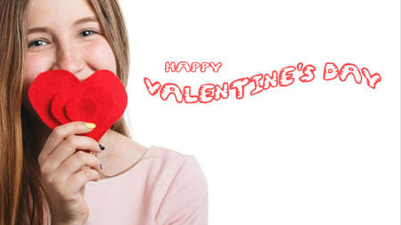 Happy Valentines day girl with red heart in hands isolated on white background. girl teenager in love and celebrating a day of loversの写真素材