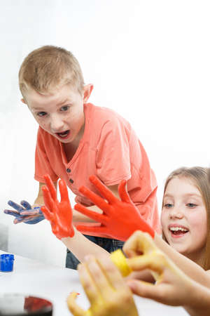 children paint with hands on the table, drawing lesson at school. schoolchildrens hands are painted...