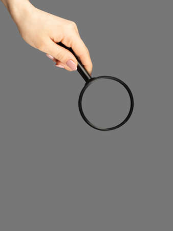 Hand holding magnifying glass isolated on gray background top view, flat lay. Web search concept.の写真素材