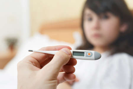close-up of the thermometer, girl is sick and lies in bed. The child has a fever, cold and flu....