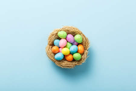 easter composition top view. eggs in the nest on blue paper background flat lay with space for text....