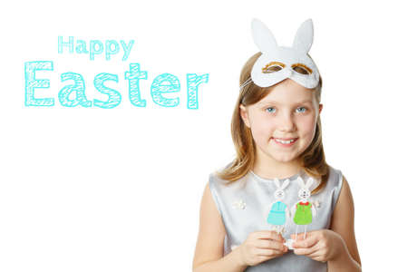 Girl with toy easter bunnies in hands on isolated white background looks into the camera and smiles. concept of Easterの写真素材