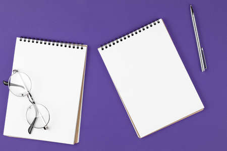 open notebook with pen and glasses on the violet background, school notebook on the purple desk,...