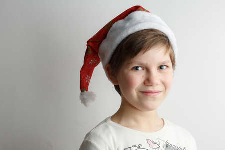 cheerful child posing in Santas red hat, festive mood, christmas and birthday