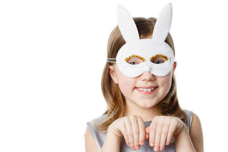 Girl in a rabbit mask isolated on white background looking at camera and smiling, showing bunny. Concept of Easterの写真素材