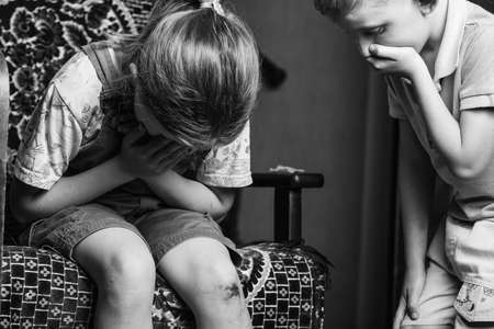 A little girl hurt her knee, a boy heals her wound. a scratched knee. brave girl.black and white.の写真素材