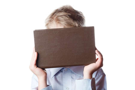 small boy hides his face behind a book, portrait on isolated white background, schoolboy with a book...