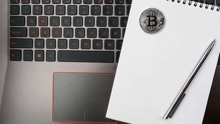 bitcoin on the keyboard, coin bitcoin on the table with the laptop, a lot of free space