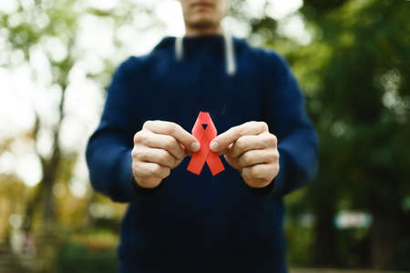 red aids ribbon in hand on green background, AIDS HIVの写真素材