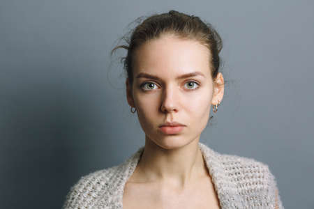 portrait of a beautiful young girl on a gray background, girl with earrings in the earの写真素材