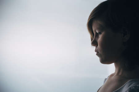 little girl cries emotional portrait, child is upset, picture with backlight and with noises for artistic purposesの写真素材