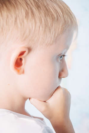 child is pondering an important decision, little boy in white t-shirt is pondering over the task, photo is isolated on a white backgroundの写真素材
