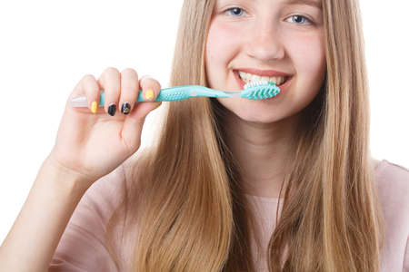 cute girl holding a toothbrush near her mouth isolated on white background, healthy teeth and proper...