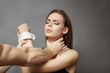 Excited pretty girl with tied hands with a rope Concept of Role playing game her neck pulled by a...