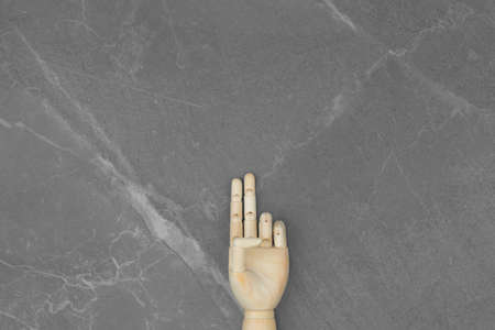 Wooden hand denoting the number two. On a gray marble isolated background.の写真素材