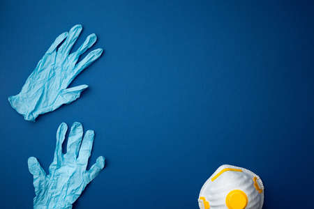 Protective respiratory face mask withl surgical gloves  on blue background flat lay. Protection...