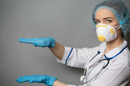 Doctor wears a protective respiratory mask, medical coat and blue rubber gloves hands measure on a...
