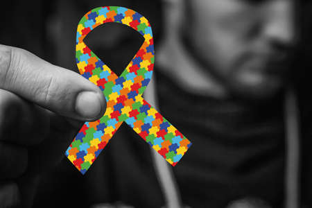 hands holding puzzle, jigsaw pattern ribbon. black and white. World Autism Awareness day